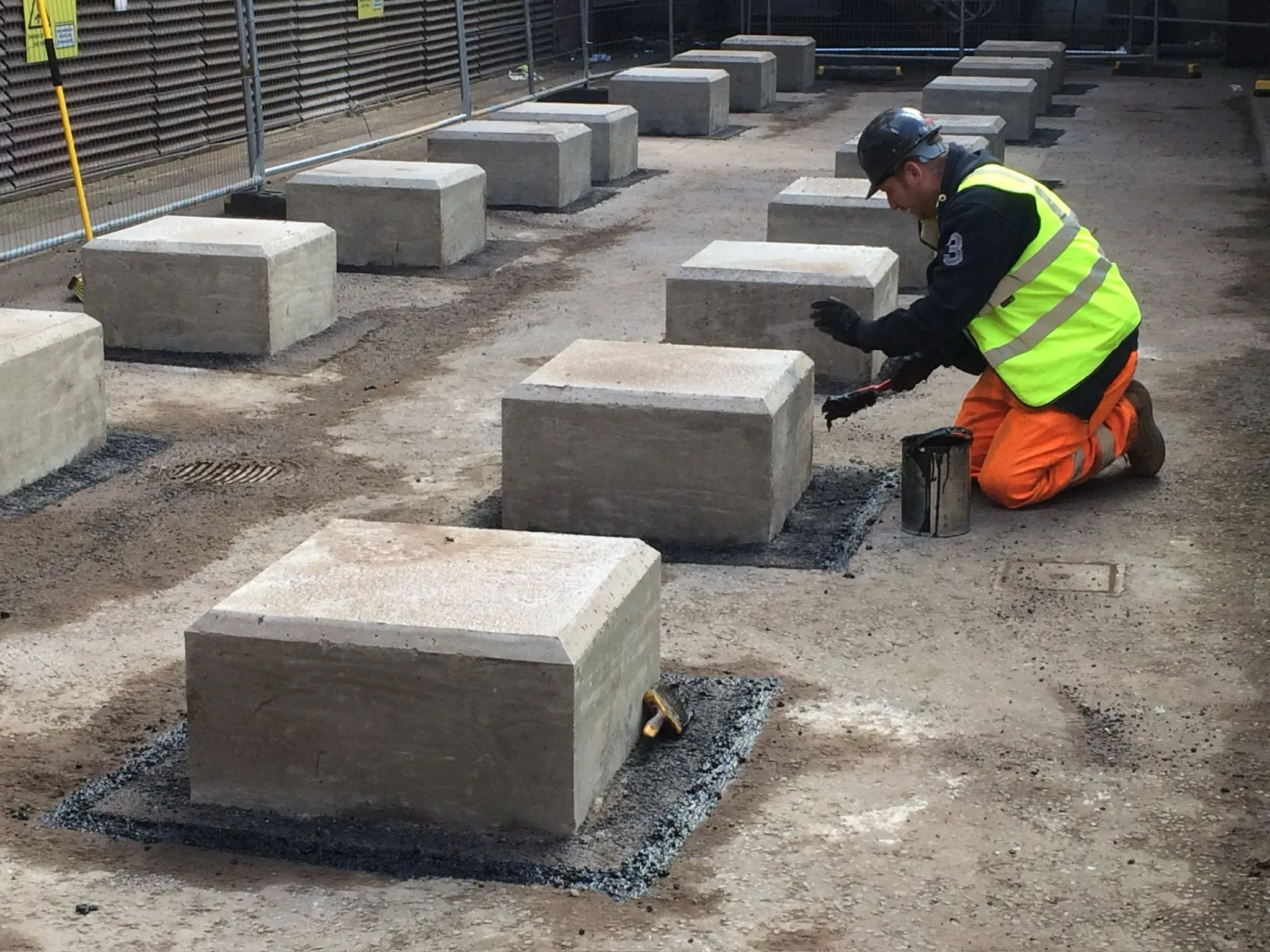 A man kneeling down next to cement blocks.